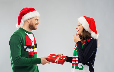 Image showing happy couple in christmas sweaters with gift box