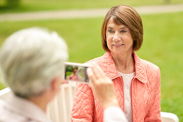 Image showing senior woman photographing her friend at park