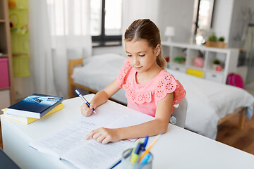 Image showing student girl with book writing to notebook at home