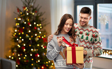 Image showing happy couple in christmas sweaters with gift box