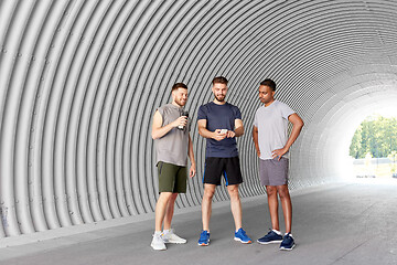 Image showing sporty men or friends with smartphone in tunnel