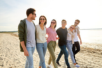 Image showing happy friends walking along summer beach
