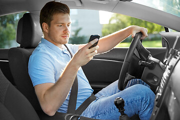 Image showing man driving car and using smartphone