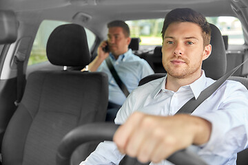 Image showing male taxi driver driving car with passenger