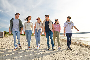 Image showing happy friends walking along summer beach