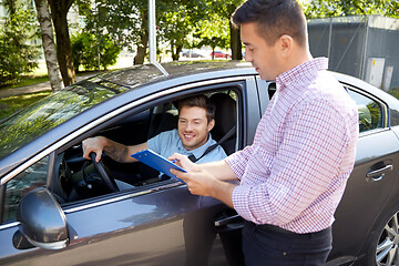 Image showing car driving instructor with clipboard and driver