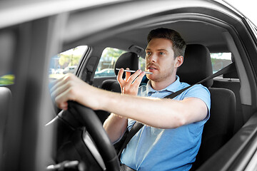 Image showing man driving car and recording voice by smartphone