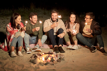 Image showing happy friends with sparklers at camp fire at night