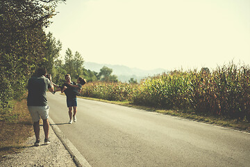 Image showing videographer recording while couple jogging along a country road