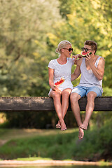 Image showing couple enjoying watermelon while sitting on the wooden bridge