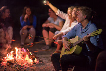 Image showing young friends relaxing around campfire