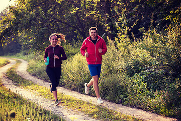 Image showing young couple jogging along a country road