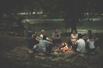 Image showing young friends relaxing around campfire