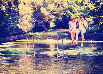 Image showing couple enjoying watermelon while sitting on the wooden bridge