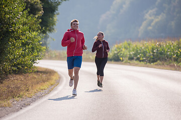 Image showing young couple jogging along a country road