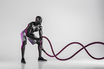 Image showing Young african-american bodybuilder training over grey background