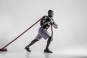 Image showing Young african-american bodybuilder training over grey background