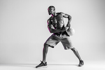 Image showing Young african-american bodybuilder training over grey background