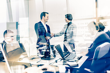 Image showing Confident business people shaking hands in moder corporate office.