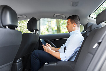 Image showing passenger with earphones and tablet pc in taxi car