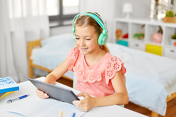 Image showing girl in headphones with tablet computer at home
