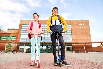 Image showing happy school children with backpacks and scooters