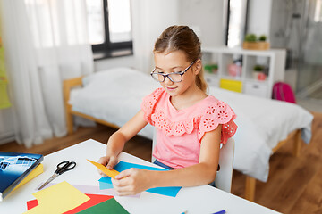 Image showing girl with color paper sitting at table at home