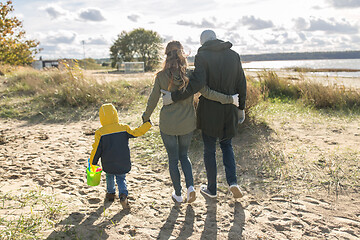 Image showing happy family walking along autumn beach