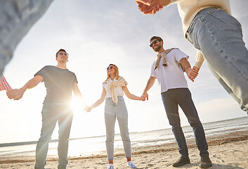 Image showing happy friends holding hands on summer beach