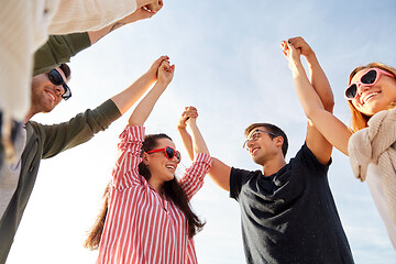 Image showing happy friends holding hands on summer beach