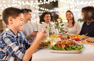 Image showing boy with smartphone at family dinner party