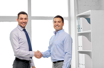 Image showing happy businessmen making handshake at office