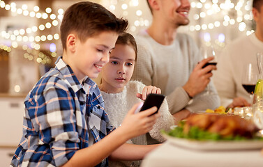 Image showing boy with sister using smartphone at family dinner