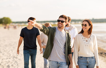 Image showing happy friends walking along summer beach