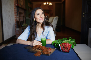 Image showing Smiling vegetarian woman sitting at the table with celery fresh 