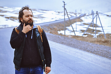 Image showing Man with backpack walking along the rural highway