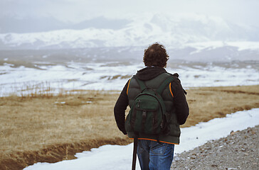 Image showing Man wearing backpack and looking at the winter mountains