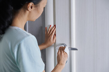 Image showing Woman cleaning the door handle with disinfecting wipe