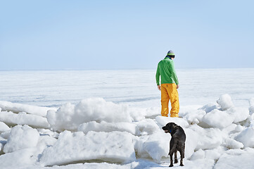 Image showing Young adult man outdoors with his dog exploring winter landscape