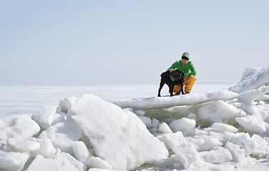 Image showing Young adult man outdoors with his dog having fun in winter lands