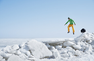 Image showing Young adult man outdoors with his dog having fun in winter lands