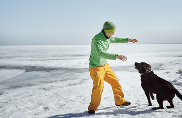 Image showing Young adult man outdoors with his dog having fun in winter lands