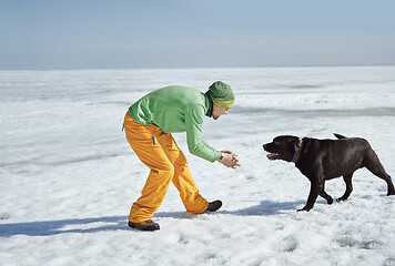 Image showing Young adult man outdoors with his dog having fun in winter lands