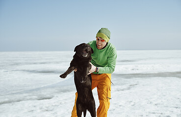 Image showing Young adult man outdoors with his dog having fun in winter lands