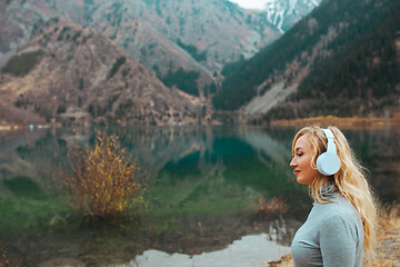 Image showing Woman wearing wireless headphones at the mountain lake