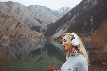 Image showing Woman wearing wireless headphones at the mountain lake