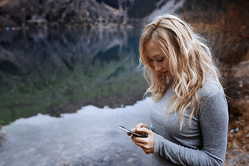 Image showing Woman using smartphone at the mountain lake