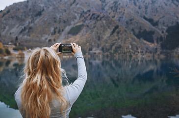 Image showing Woman making mobile photo at the mountain lake