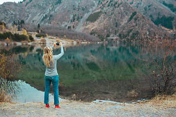 Image showing Woman making mobile photo at the mountain lake