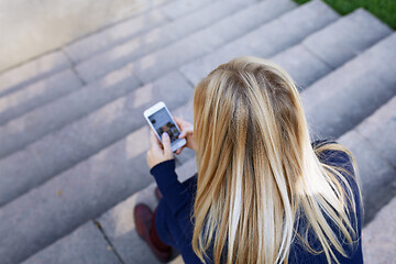 Image showing Business woman sitting on city stair steps and holding smartphon